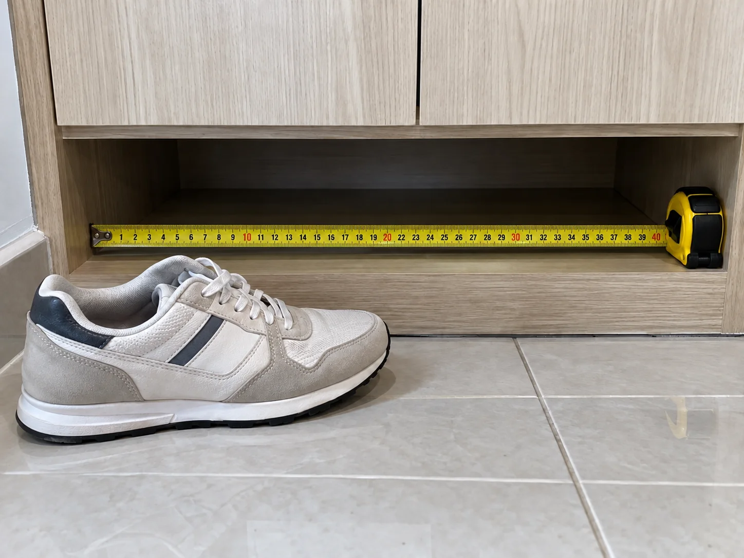 Measuring tape showing the depth and height of the open gap under a shoe cabinet